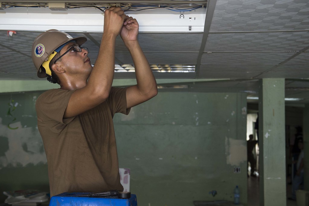 A tradesman installing a ceiling light fixture